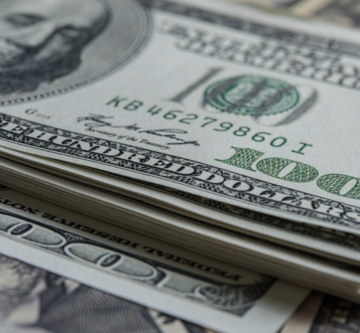 A stack of money with a $100 note in front